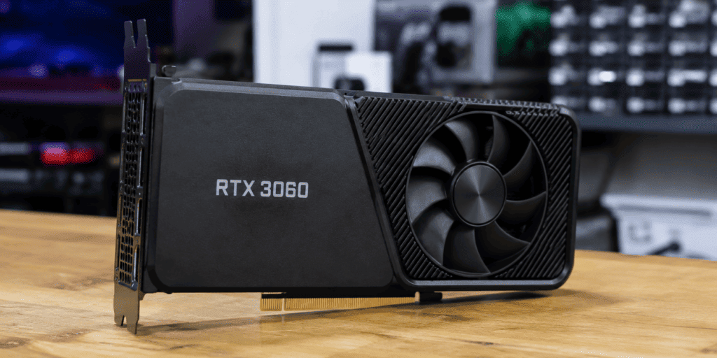 RTX 3060 graphics card on a wooden table, showing its PCIe edge connector and large cooling fan.
