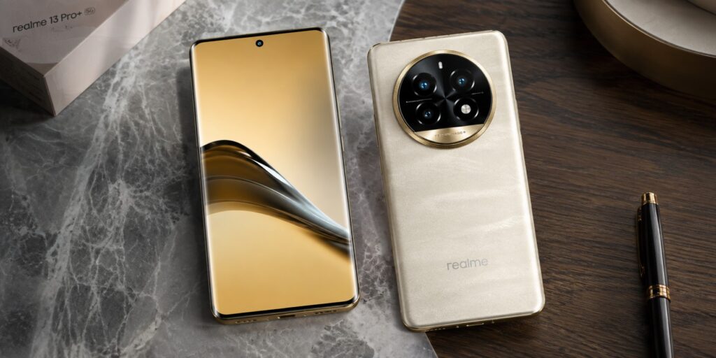 Realme 13 Pro Plus 5G smartphone showing its premium gold back with a large circular camera module and curved AMOLED display on a desk.