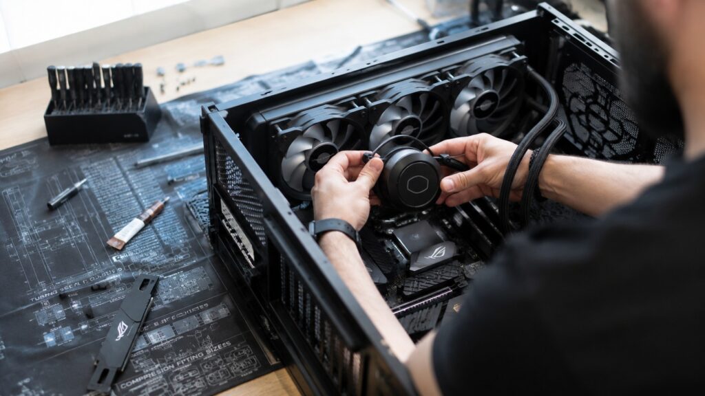 Over-the-shoulder view of a person mounting a CPU cooler inside an open desktop PC case.