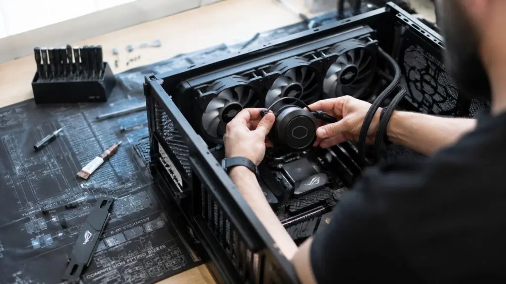 Over-the-shoulder view of a person mounting a CPU cooler inside an open desktop PC case.